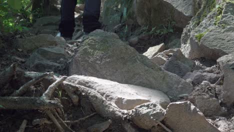 feet in hiking boots climb a trail that leads over stony terrain