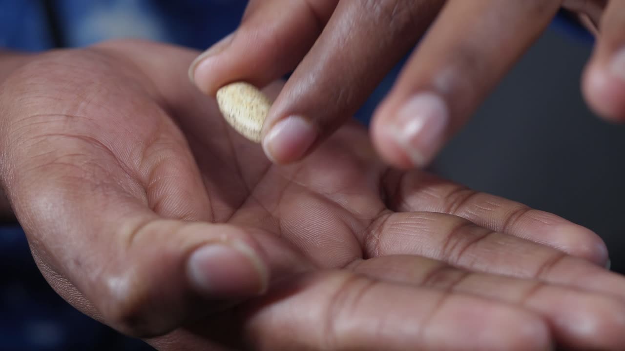 Hand holding a brown pill