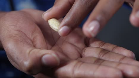 hand holding a brown pill