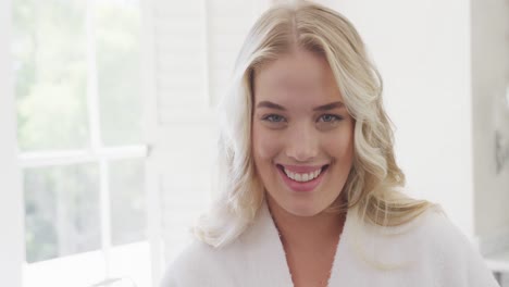 Portrait-of-happy-caucasian-plus-size-woman-wearing-bathrobe-in-bathroom-in-slow-motion