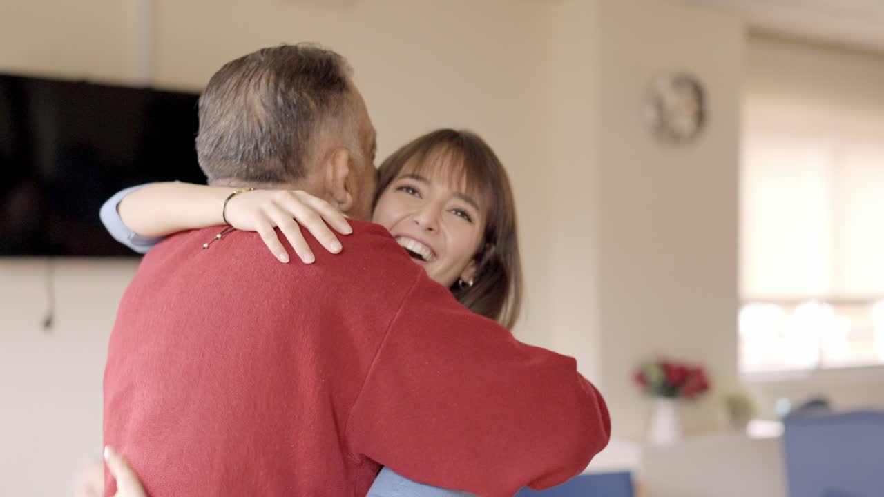 Adult granddaughter embracing her grandfather visiting him in a geriatric
