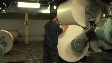 los trabajadores observan los rodillos de papel en la fábrica de periódicos 1