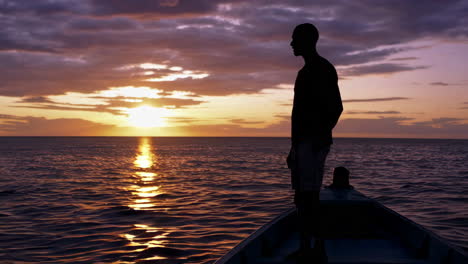 silhouetted figure on a boat at sunset