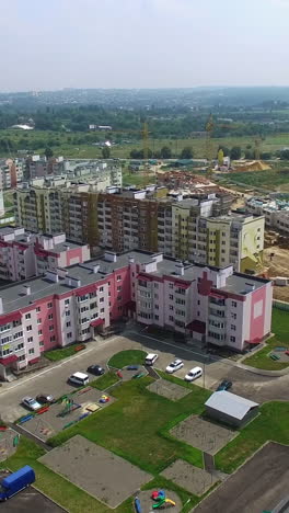 flying above new residential complex in the city in summer. panoramic top view of modern buildings built in the new district. aerial view vertical video