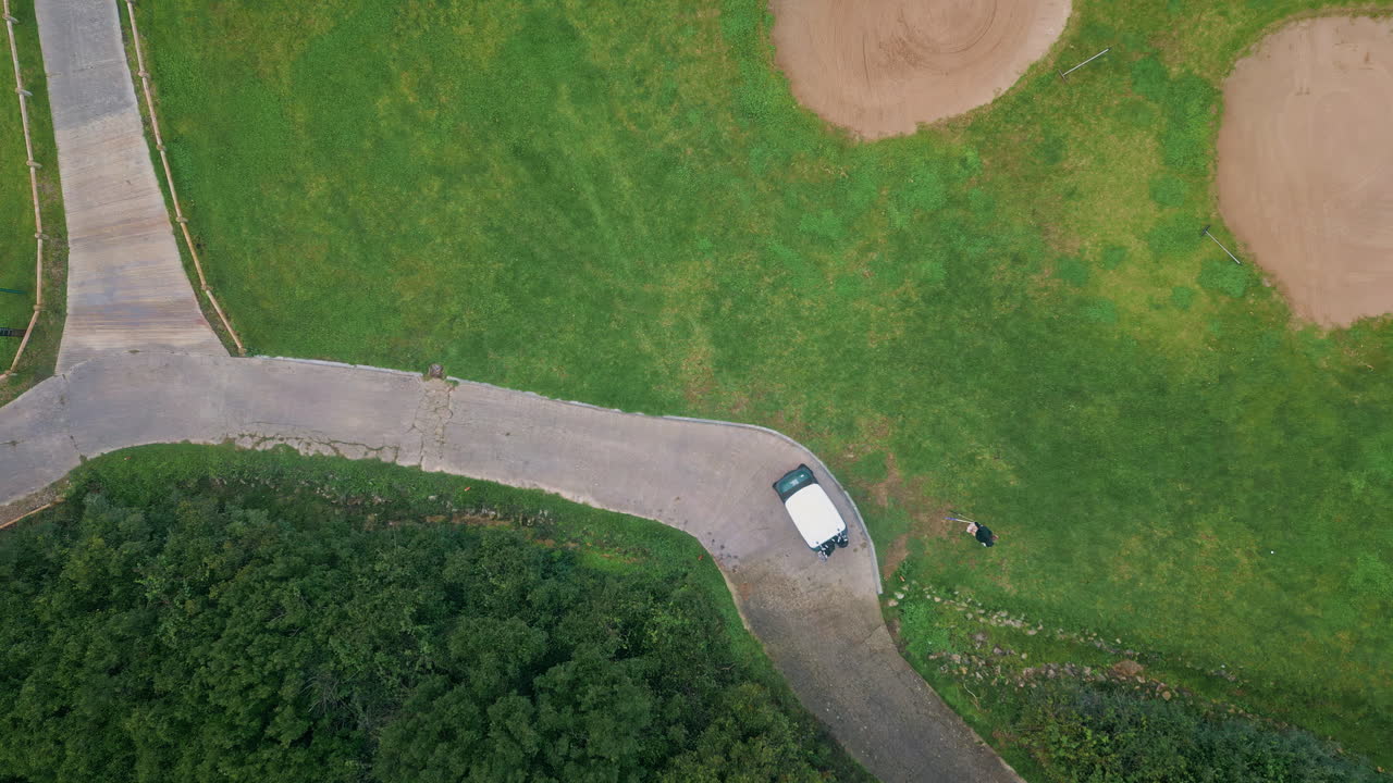 Aerial golf cart standing on winding path of lush green fairway. Golf course