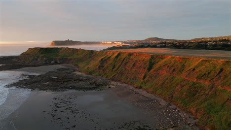 establishing aerial drone shot of cleveland way at golden hour with scarborough castle in background