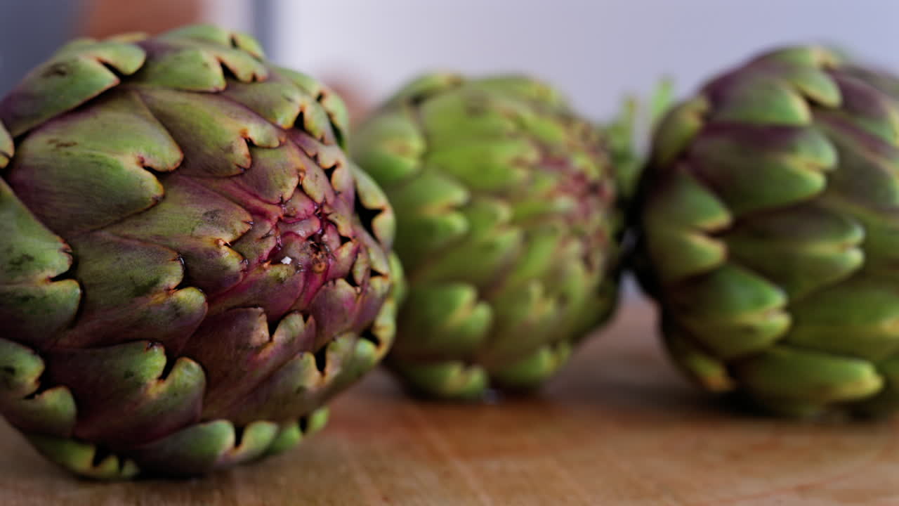 Primo piano di tre carciofi su un tavolo di legno