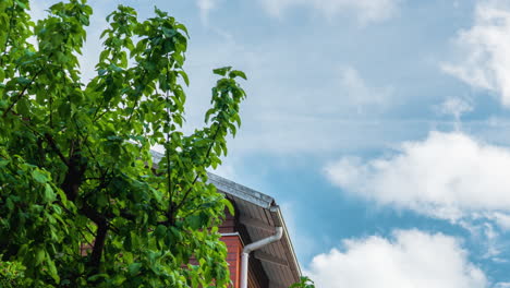 Zeitraffer-Eines-Hellen-Sommertages-Mit-Weißen-Wolken,-Die-Sich-Schnell-Hinter-Einem-Finnischen-Haus-Aus-Ziegeln-Bewegen