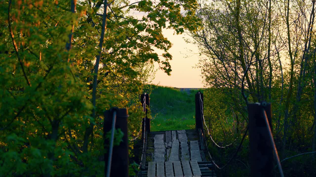 antiguo puente peatonal de madera que conduce a la carretera con el coche conduciendo lentamente al atardecer