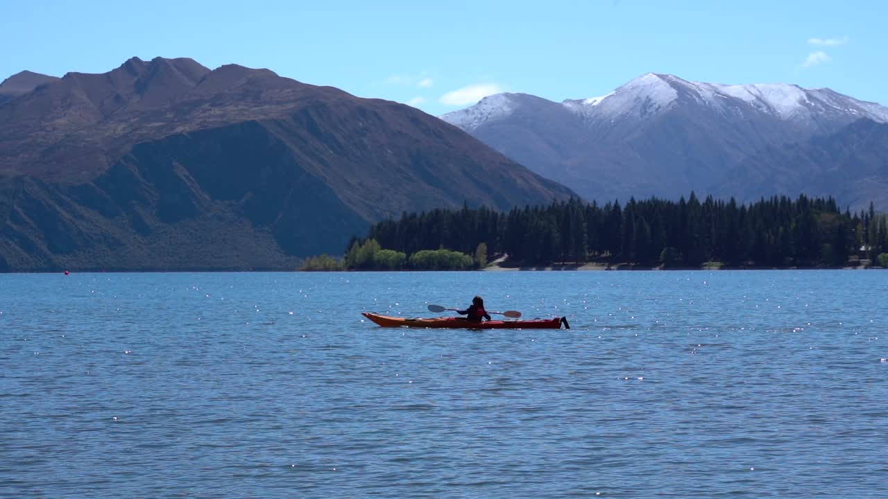 una mujer en kayak en el lago wanaka, nueva zelanda en un día soleado