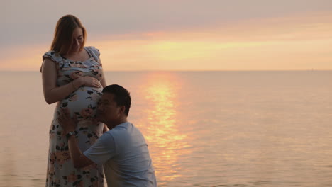 Young-Asian-Man-Put-His-Ear-To-The-Belly-Of-His-Pregnant-Caucasian-Wife
