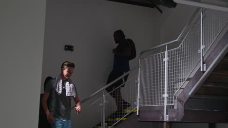 atletas masculinos y femeninos en ropa de fitness entrenando en el gimnasio bajando las escaleras a los vestuarios antes o después del ejercicio 1