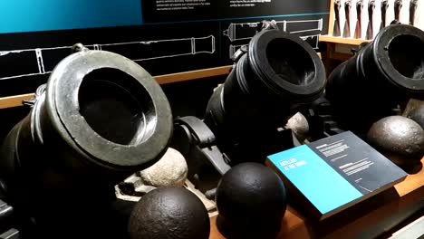 panning shot of short cannons and cannonballs on display within the tower of london