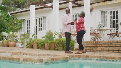 a senior african american couple dancing in the garden in social distancing