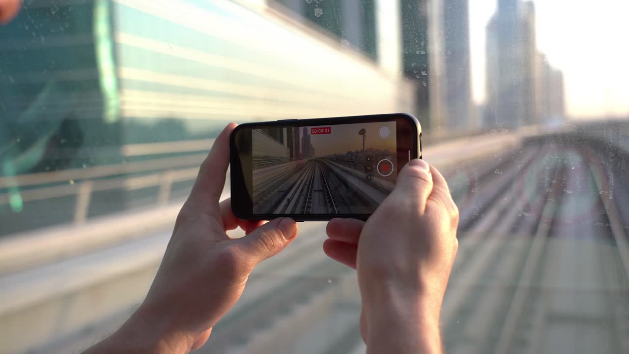 turista con smartphone grabando video del ferrocarril del metro de dubai desde el frente del tren en movimiento 60fps