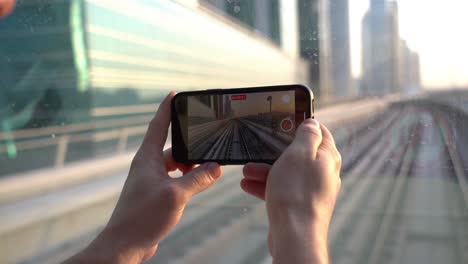 tourist with smartphone recording video of railroad of dubai metro from front of moving train 60fps