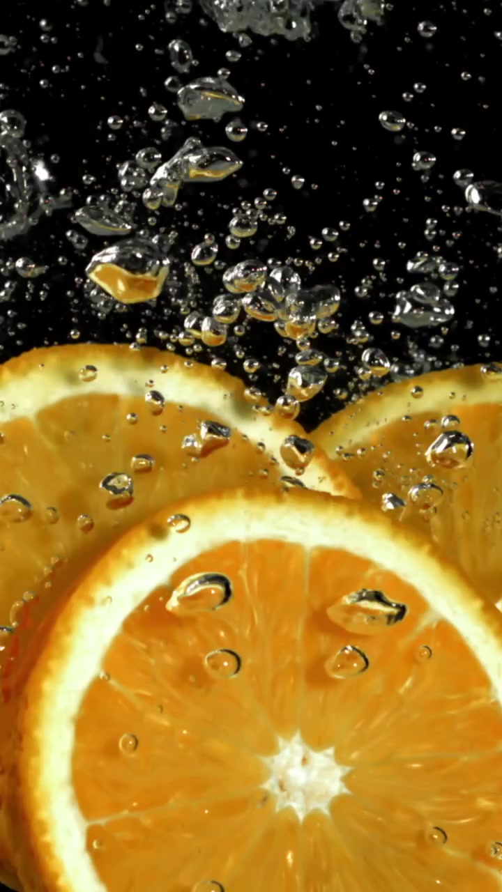Fette d'arancia al rallentatore immerse nell'acqua con bolle