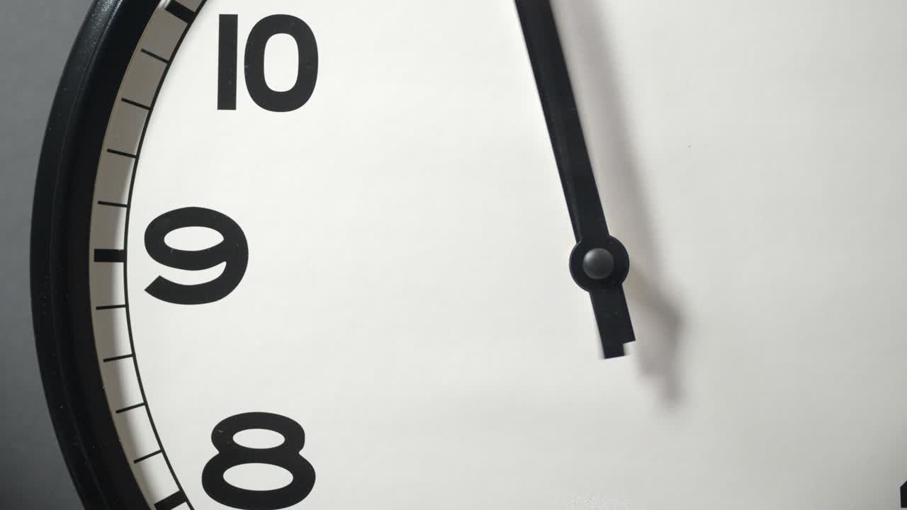White Clock Face Close Up in Time Lapse on Dark Grey Wall