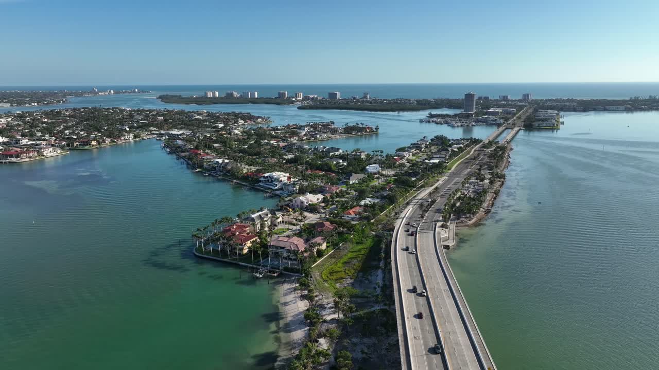 Traffic on bridge in Florida connecting Sarasota and St. Armands District during sunny day. Aerial wide shot. Gulf of America and bay in distance.