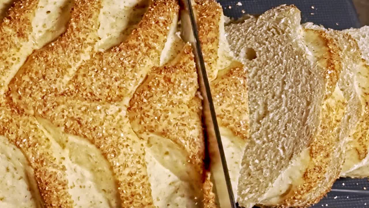Freshly homemade tasty bread, serrated electrical knife, food preparation