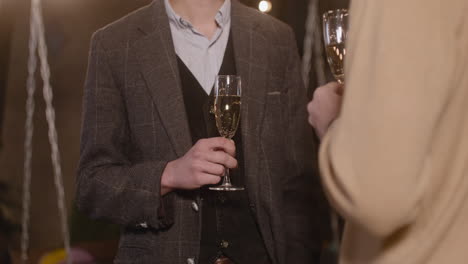 two elegant men talking to each other and drinking champagne at new year's eve party 1