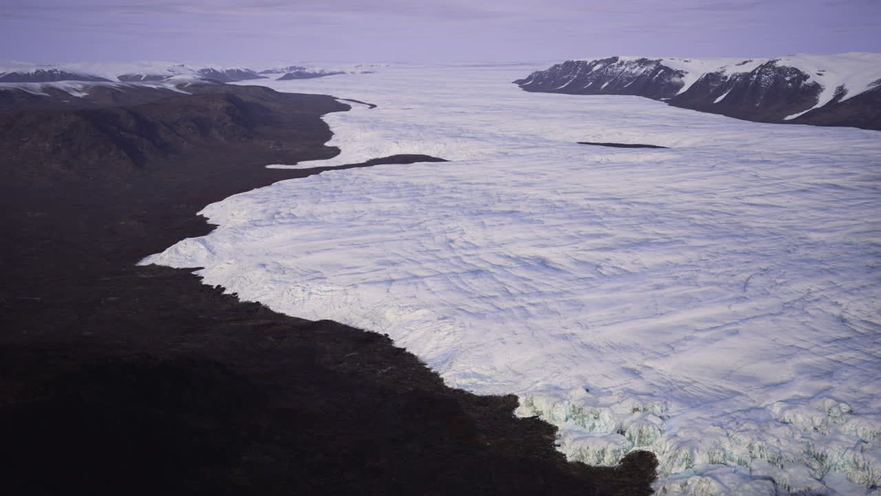 遠くのグリーンランドの火山海岸が、氷と岩の地形を見せる