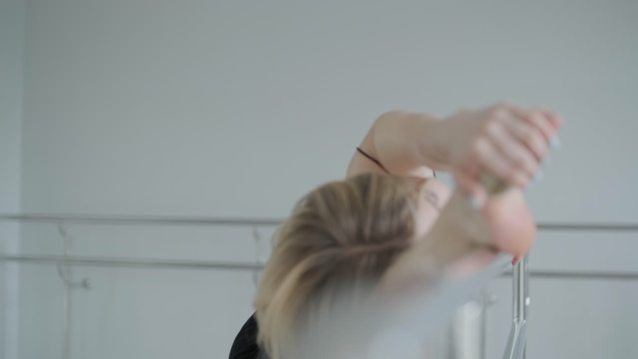 девушка в черной одежде выступает в современном стиле. танцовщица показывает плавные движения, волны тела и рук в белой комнате. современная балетная танцевальная хореография. молодая женщина движется плавно