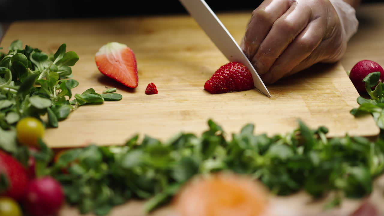 Person cutting strawberries on a wooden board