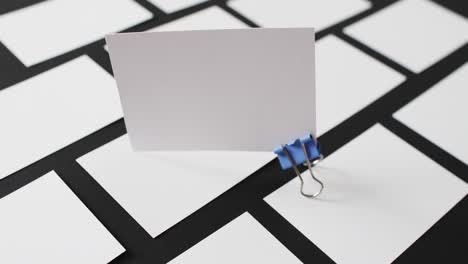 blank white business card with bulldog clip standing on other blank cards, copy space, slow motion