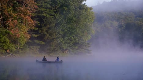 fishing canoe on a foggy morning with mist floating over a pond