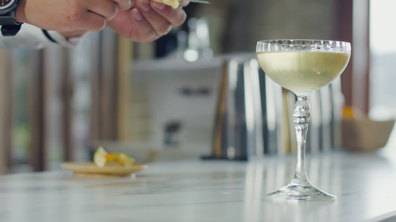 Close-up of a bartender placing a garnish on a cocktail glass at a modern bar