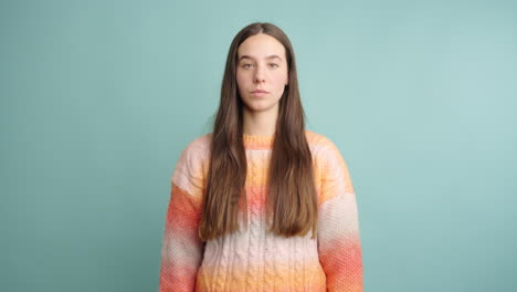 young woman with serious expression on turquoise background