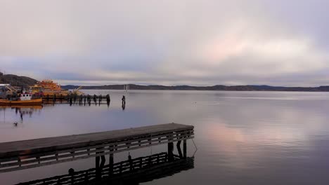 the peaceful fishing dock of lysekil, sweden with mountains in the background - low aerial