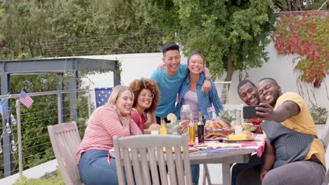 Fröhliche,-Vielfältige-Gruppe-Von-Freunden,-Die-Selfie-Am-Esstisch-Im-Garten-Machen,-Zeitlupe