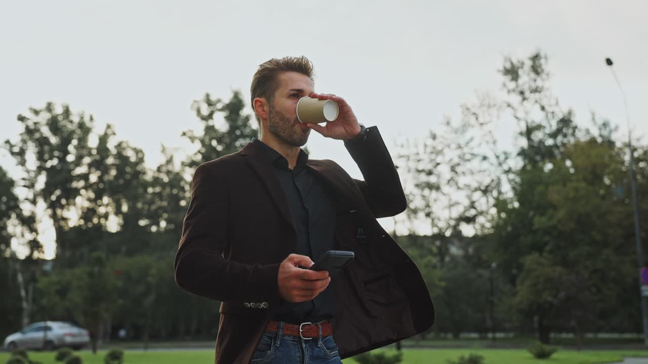 Businessman drinking coffee and using phone outdoors