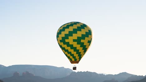 peaceful scene of yellow and green hot air balloon in sky