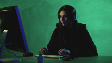 Frau,-Die-Mit-Einem-Computer-Und-Drahtlosen-Kopfhörern-Auf-Einem-Grünen-Farbigen-Hintergrund-Arbeitet