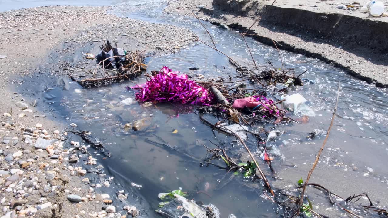 Rubbish and household trash washing down river into ocean in tropical island destination