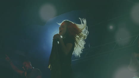 female singer performing while male singer pointing under stage spotlights showing sound wave icons
