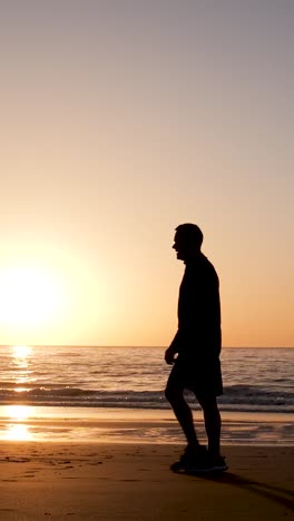 silhouette of a man walking on the beach at sunset