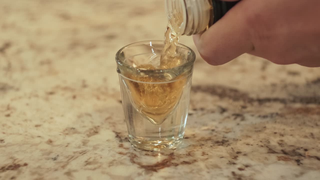 Pouring of alcohol into shot glass. Closeup