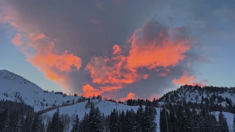 stunning winter sunset with vivid orange and pink colors above a large ski resort in the rocky mountains of utah on a cold winter evening