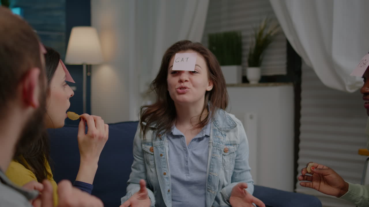 amigos multiétnicos sentados en el sofá tarde en la noche jugando al juego de adivinar quién