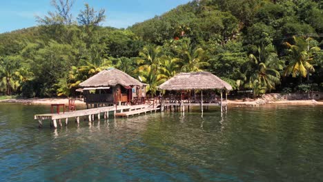 schwimmendes restaurant mit strohdach steht auf holzstangen über dem wasser