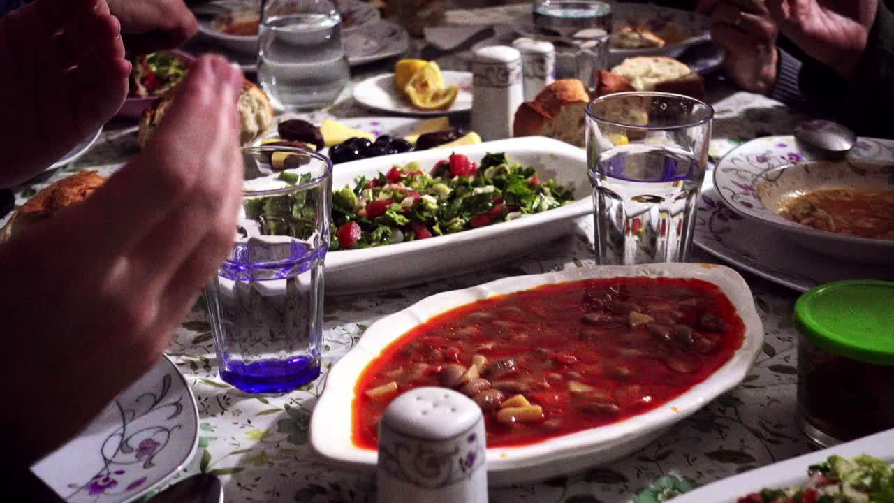 una familia musulmana turca abarrotada en la mesa del iftar orando y agradeciendo a alá