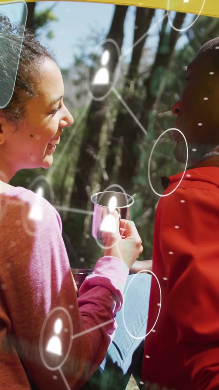 Vertikální video: Žena zvedající šálek a smějící se, ukazující technologické ikony, profily nad párem pro propojení na mapě.