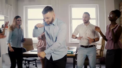 young european businessman dancing together with colleagues at fun casual office party, celebrating career promotion 4k