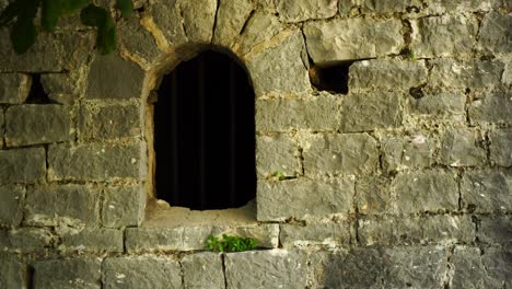 ventana de la mazmorra desde el exterior del grueso muro de piedra de la prisión de la fortaleza medieval