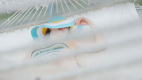 a cute girl enjoys relaxing smiling swinging on a white sunbed on the ocean coast