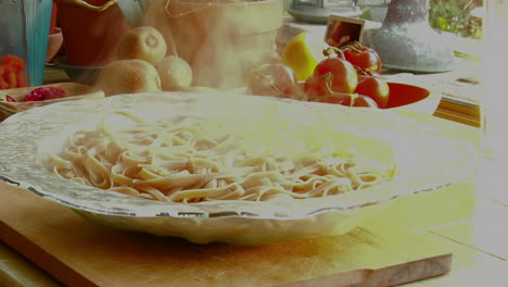 a woman chef prepares a meal by pouring fresh cooked pasta into a glass bowl